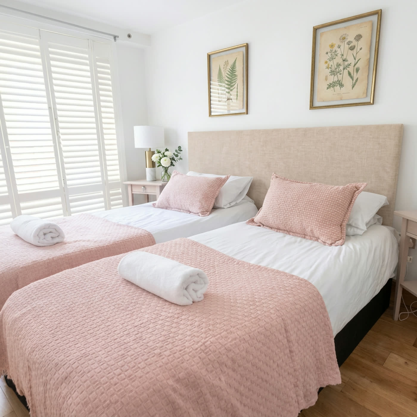Twin bedroom with blush pink bedding, linen headboard and botanical prints