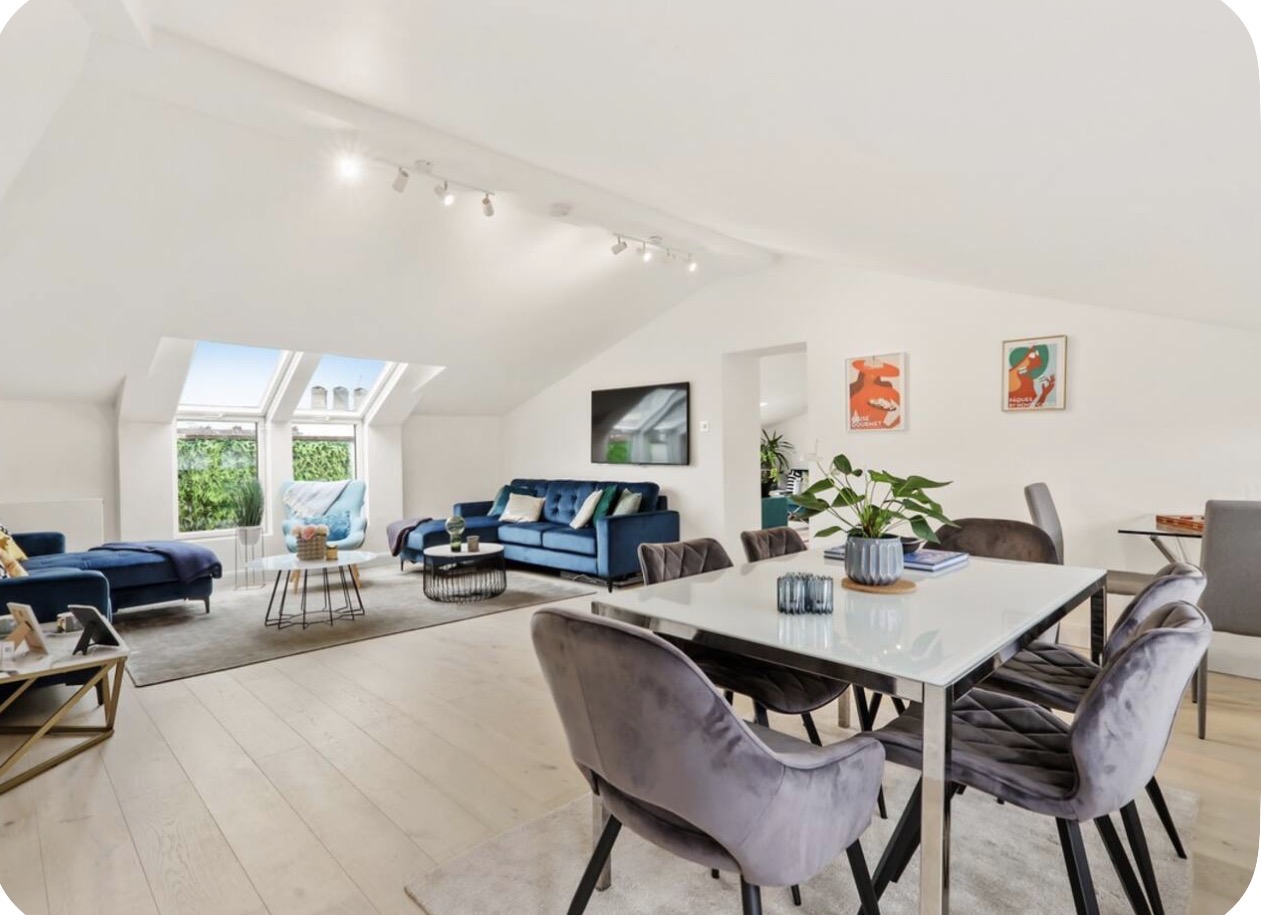 Open-plan penthouse living and dining room with vaulted ceiling and skylights