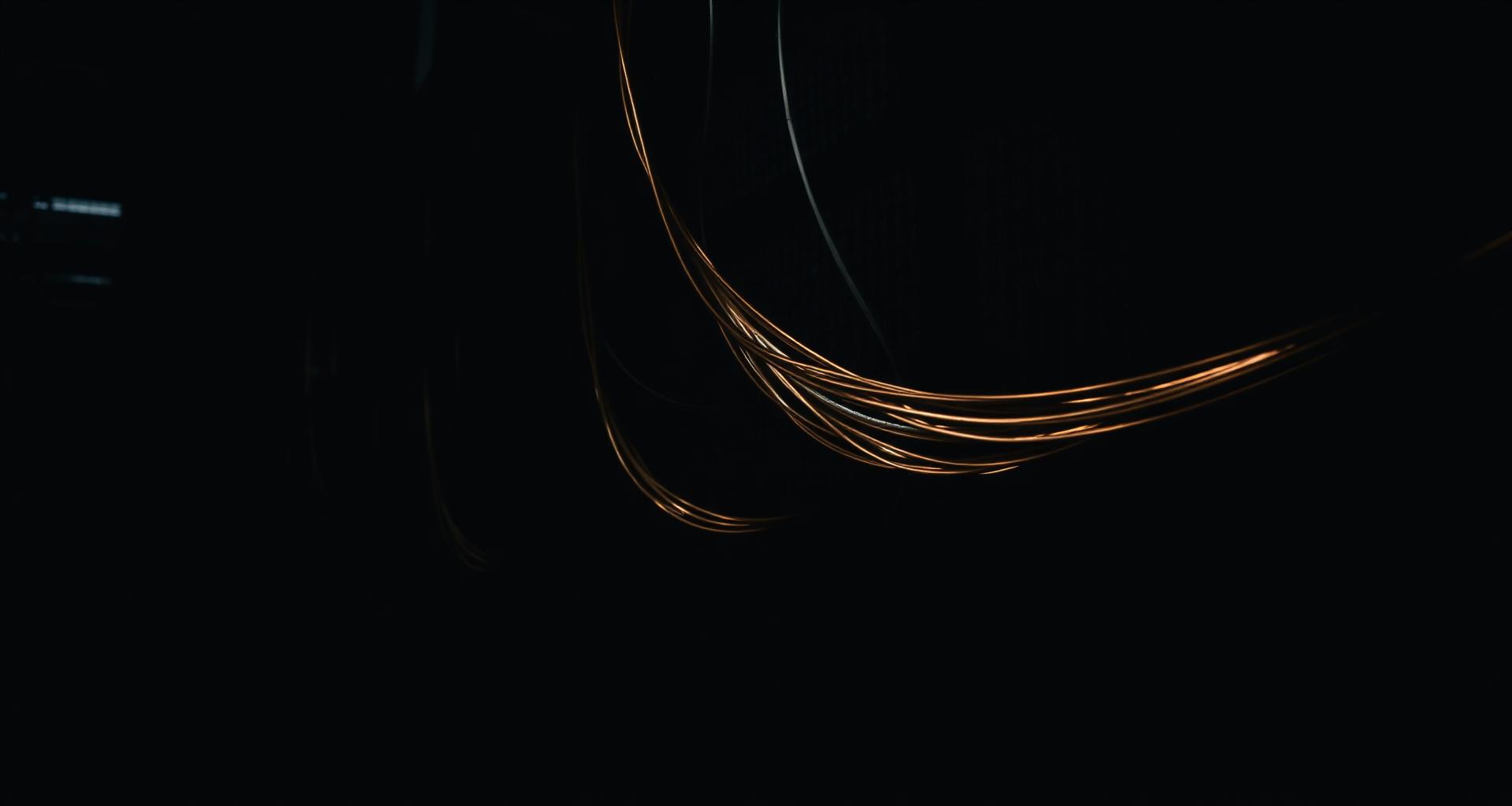 Electrical cables with warm copper light against a dark background